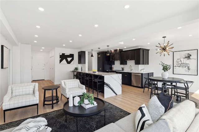 living room with recessed lighting, a notable chandelier, and light wood-style floors