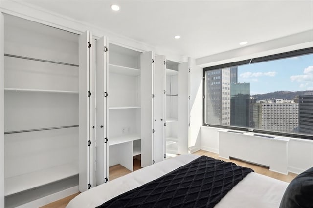 bedroom with a city view, recessed lighting, and wood finished floors