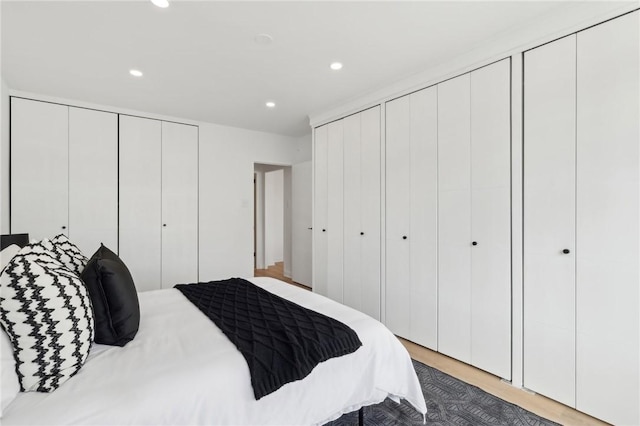 bedroom with recessed lighting, two closets, and wood finished floors