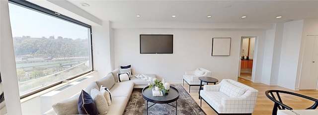living room with recessed lighting, plenty of natural light, baseboards, and light wood-type flooring