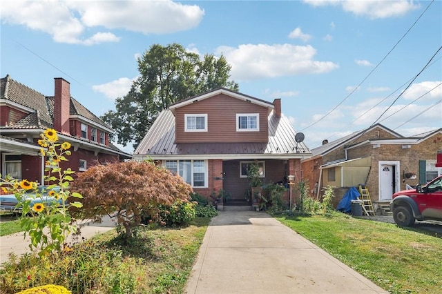 view of front of house featuring metal roof, brick siding, a front yard, and a standing seam roof