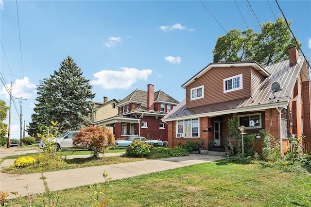 view of front of property with a front yard, metal roof, brick siding, and a chimney