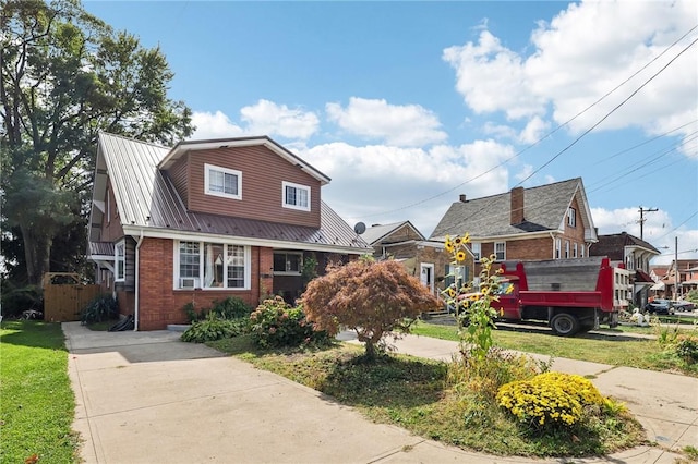 view of front of home featuring brick siding, metal roof, and fence