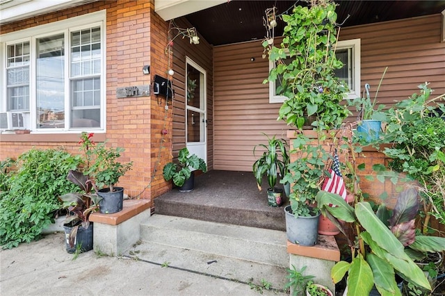 view of exterior entry featuring a porch and brick siding