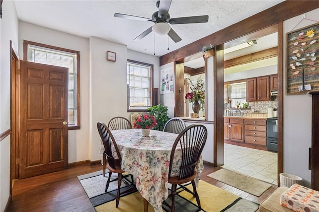 dining area with a wealth of natural light, baseboards, light wood-style floors, and beam ceiling