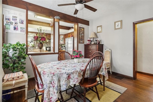 dining room featuring wood finished floors, baseboards, visible vents, beam ceiling, and ceiling fan