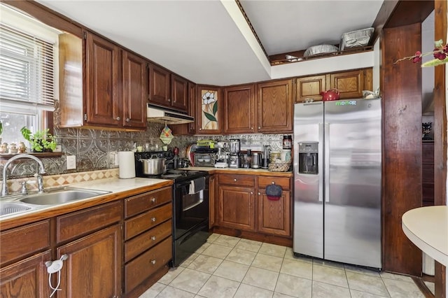 kitchen featuring black range with electric stovetop, stainless steel refrigerator with ice dispenser, under cabinet range hood, a sink, and light countertops