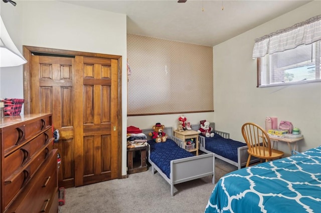 carpeted bedroom featuring wallpapered walls and ceiling fan