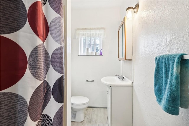 full bathroom with toilet, vanity, and wood finished floors