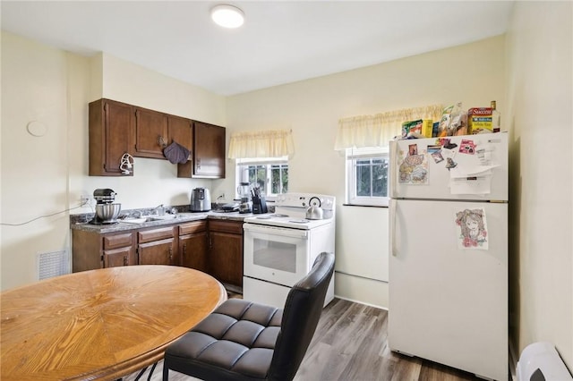 kitchen featuring visible vents, light countertops, wood finished floors, white appliances, and a sink