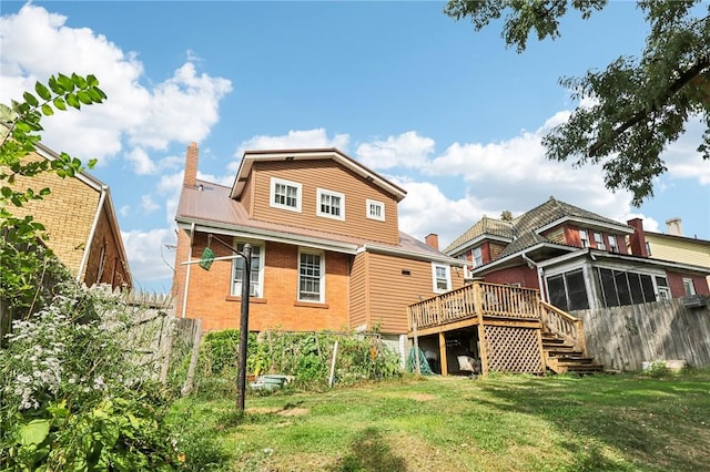 back of house with a yard, brick siding, a deck, and fence