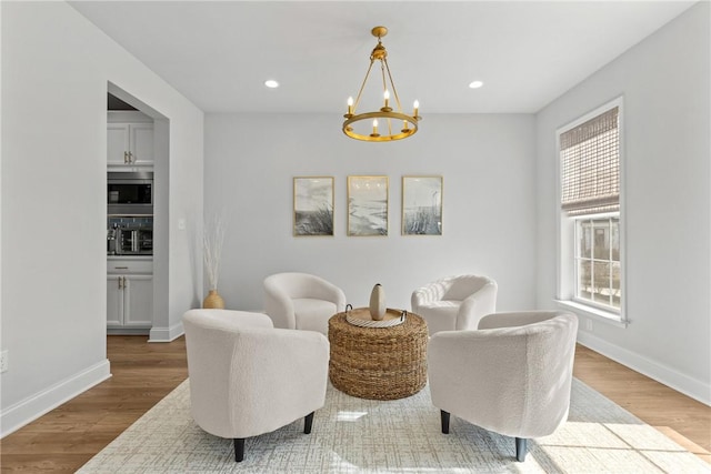 living area featuring recessed lighting, an inviting chandelier, baseboards, and wood finished floors