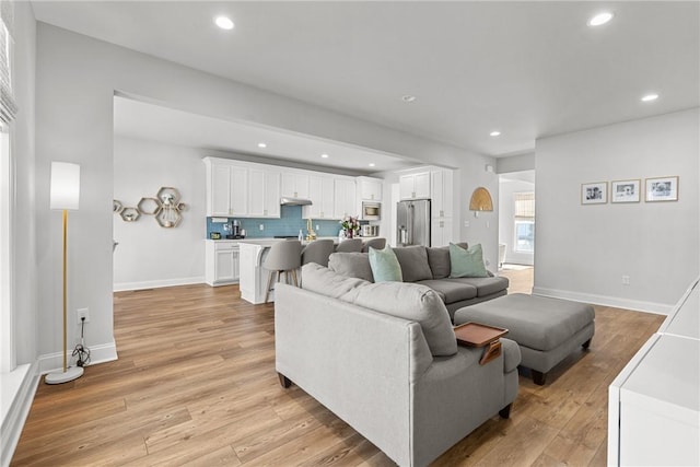 living area featuring recessed lighting, baseboards, and light wood-style floors