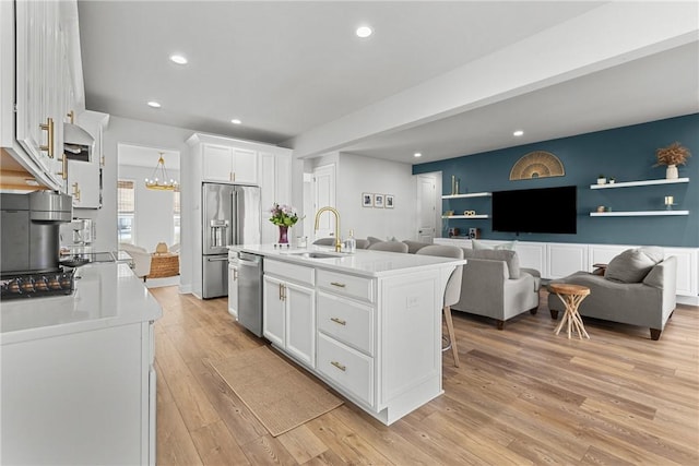 kitchen featuring light wood-style flooring, stainless steel appliances, a sink, light countertops, and white cabinets