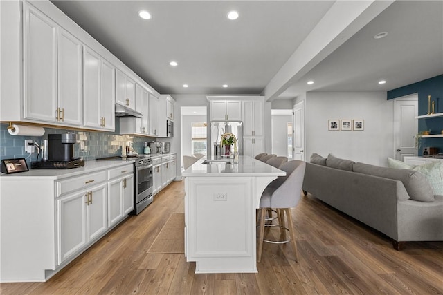 kitchen featuring white cabinets, open floor plan, appliances with stainless steel finishes, and a sink