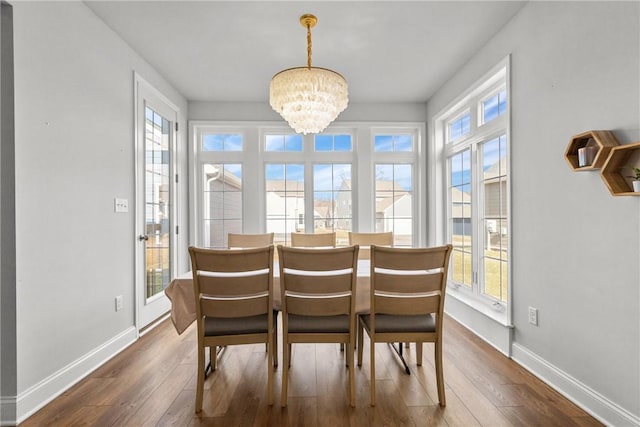 dining room with dark wood finished floors, an inviting chandelier, and baseboards