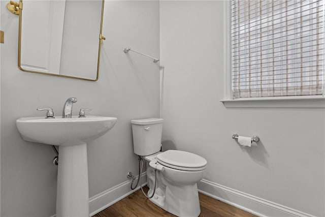 bathroom featuring toilet, wood finished floors, baseboards, and a sink