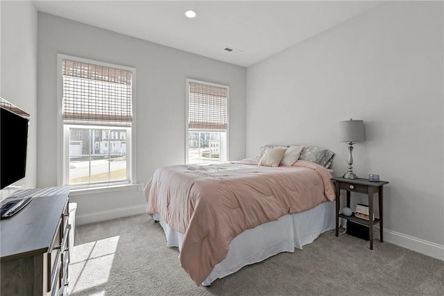 bedroom featuring multiple windows, light carpet, and baseboards