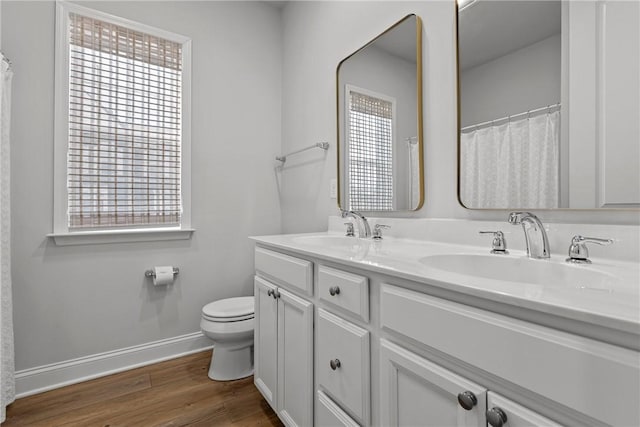 full bath with toilet, wood finished floors, baseboards, and a sink