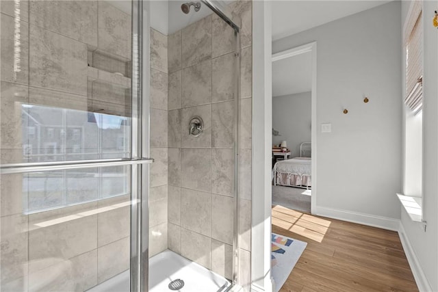 ensuite bathroom featuring baseboards, wood finished floors, ensuite bath, and a stall shower