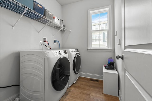 washroom with baseboards, visible vents, light wood-type flooring, laundry area, and independent washer and dryer