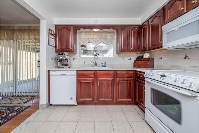 kitchen with white appliances, plenty of natural light, a sink, light countertops, and reddish brown cabinets