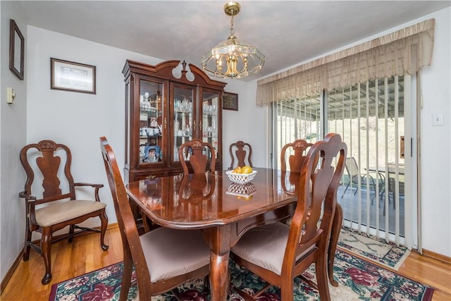 dining room with a chandelier, baseboards, and wood finished floors