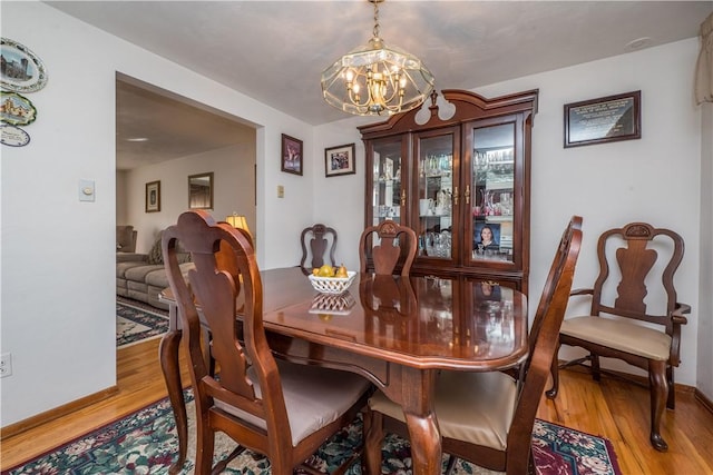 dining room featuring a chandelier, baseboards, and wood finished floors