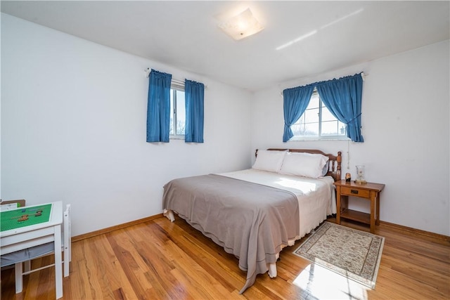 bedroom featuring light wood finished floors and baseboards