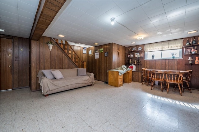 living area featuring stairs, tile patterned floors, and wooden walls