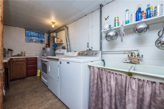 clothes washing area featuring laundry area, washing machine and dryer, and concrete block wall