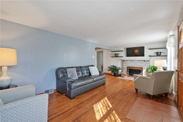 living area featuring visible vents, baseboards, wood finished floors, and a fireplace