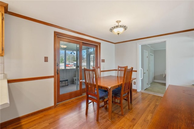 dining area with light wood-type flooring, baseboards, and ornamental molding