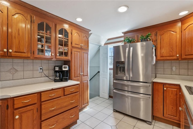 kitchen featuring brown cabinets, stainless steel appliances, glass insert cabinets, and light countertops