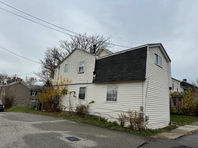 view of property exterior featuring a gambrel roof and a shingled roof