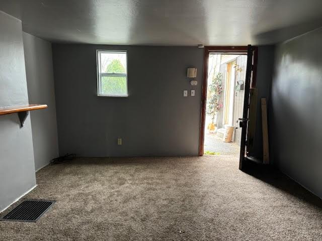 carpeted empty room featuring visible vents