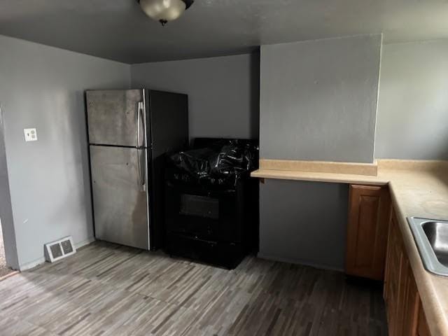 kitchen featuring gas stove, light wood-style flooring, light countertops, and freestanding refrigerator