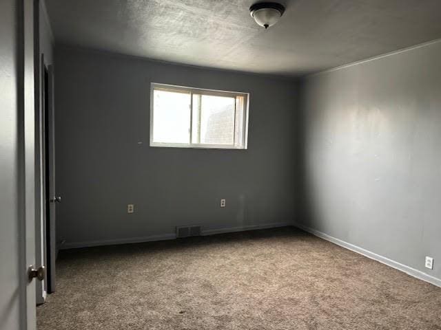 carpeted empty room featuring baseboards and visible vents