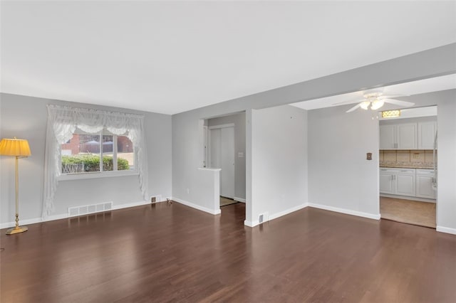 unfurnished living room with visible vents, a ceiling fan, baseboards, and wood finished floors