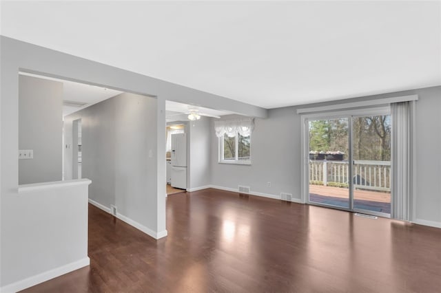 empty room with ceiling fan, wood finished floors, visible vents, and baseboards