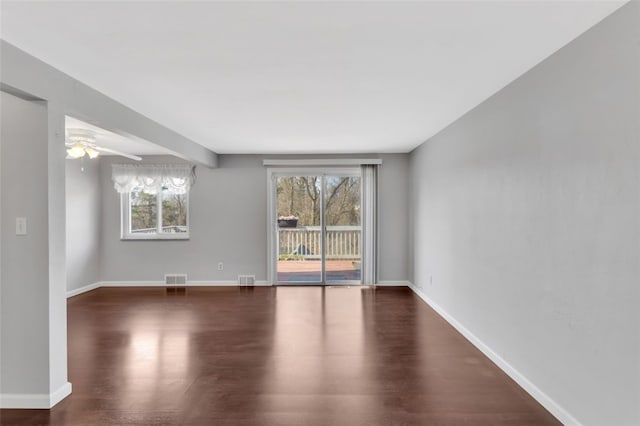 unfurnished room featuring a wealth of natural light, baseboards, and dark wood-style flooring