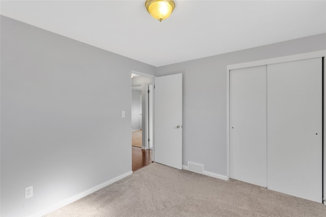 unfurnished bedroom with a closet, visible vents, carpet flooring, and baseboards