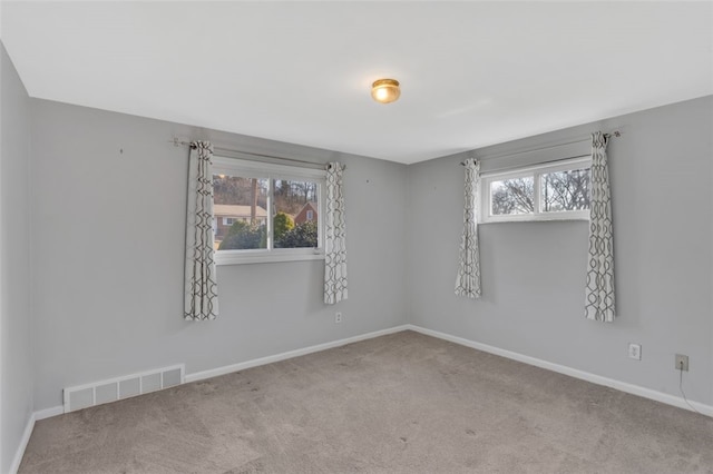 spare room with carpet flooring, baseboards, and visible vents