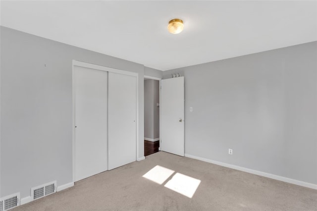 unfurnished bedroom featuring a closet, visible vents, baseboards, and carpet floors