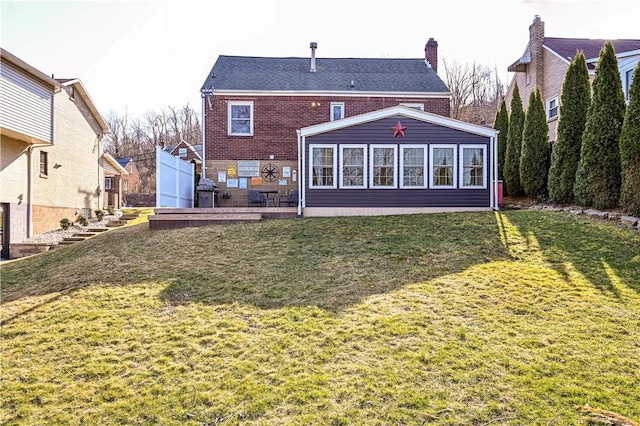 rear view of house featuring stairs, a yard, brick siding, and a chimney