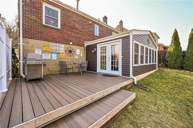 wooden terrace featuring fence, french doors, a lawn, and a grill