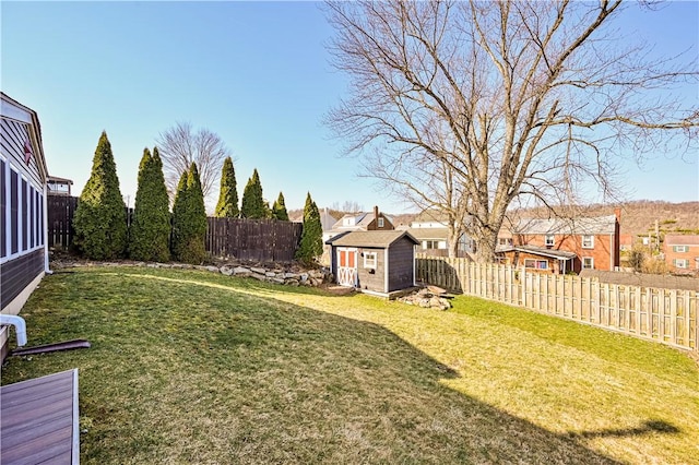 view of yard with an outbuilding, a residential view, a storage shed, and a fenced backyard