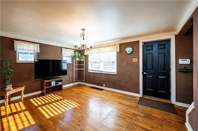 entryway featuring hardwood / wood-style floors, a notable chandelier, visible vents, and baseboards