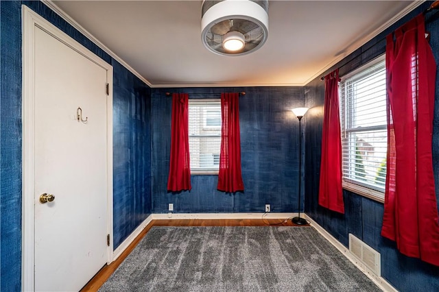 spare room with visible vents, wood finished floors, baseboards, and ornamental molding