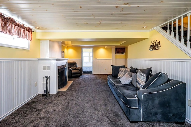 living area with visible vents, dark carpet, a fireplace, wainscoting, and wood ceiling